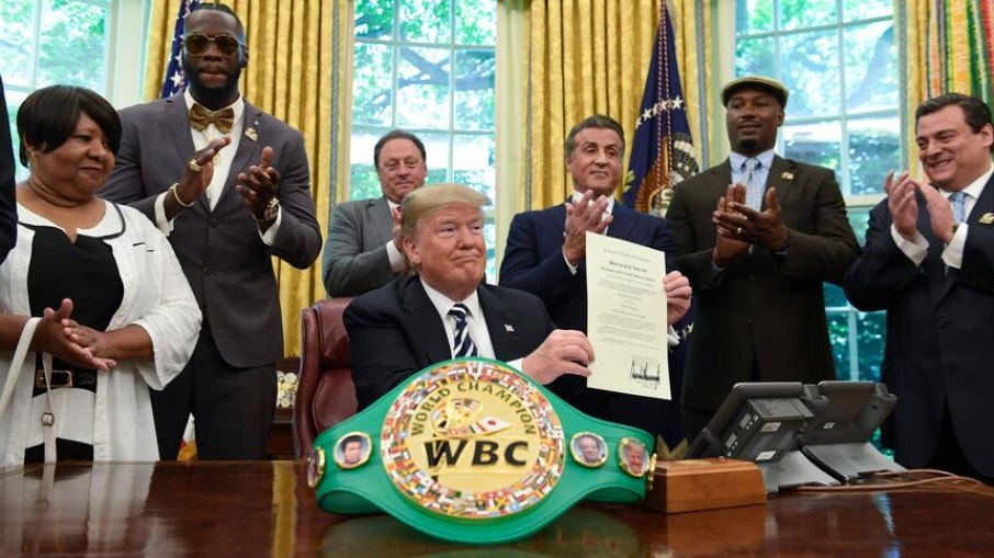 (Susan Walsh/Associated Press) O presidente Donald Trump concedeu um perdão póstumo a Jack Johnson na quinta-feira. Trump aparece acompanhado, da esquerda para a direita, por Linda Haywood, que é sua trineta, pelo campeão dos pesos-pesados Deontay Wilder, Keith Frankel, Sylvester Stallone, o ex-campeão dos pesos-pesados Lennox Lewis e o presidente do Conselho Mundial de Boxe, Mauricio Sulaimán.