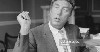 O comediante e ator inglês Frankie Howerd (1917-1992) sentado em uma mesa em casa em julho de 1966. (Foto de Popperfoto via Getty Images)