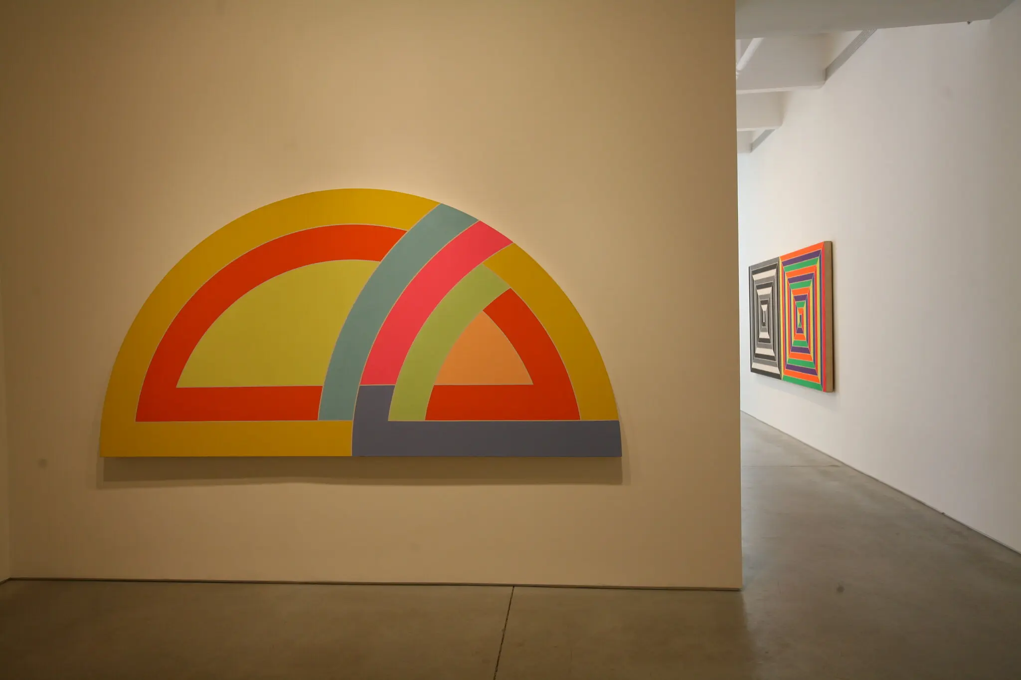 “Variação do Transferidor IX” (1968). Na série “Transferidor” de Stella, mais de 100 pinturas em tamanho mural estavam repletas de semicírculos sobrepostos de cores brilhantes, às vezes fluorescentes.Crédito...Frank Stella/Artists Rights Society (ARS), Nova York; Chester Higgins Jr.,/The New York Times