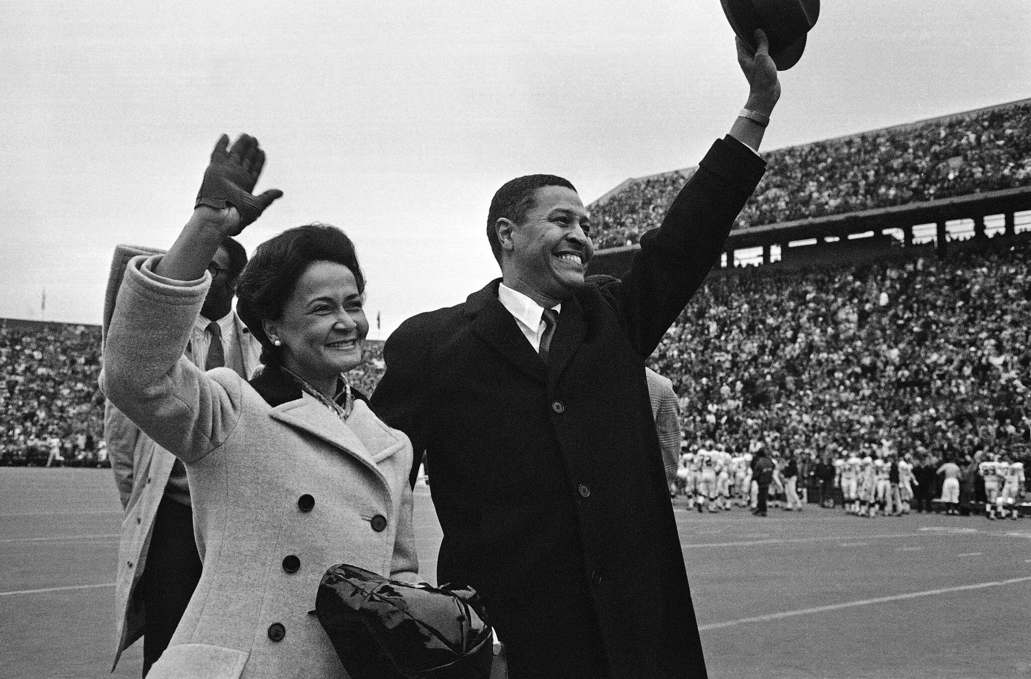 Clifton R. Wharton e sua esposa, Dolores, são recebidos com uma ovação estrondosa em 1969, quando ele é apresentado como presidente eleito do Michigan State diante de 77.000 fãs em um jogo de futebol americano do Michigan State em East Lansing. (Crédito da fotografia: cortesia Imprensa associada)