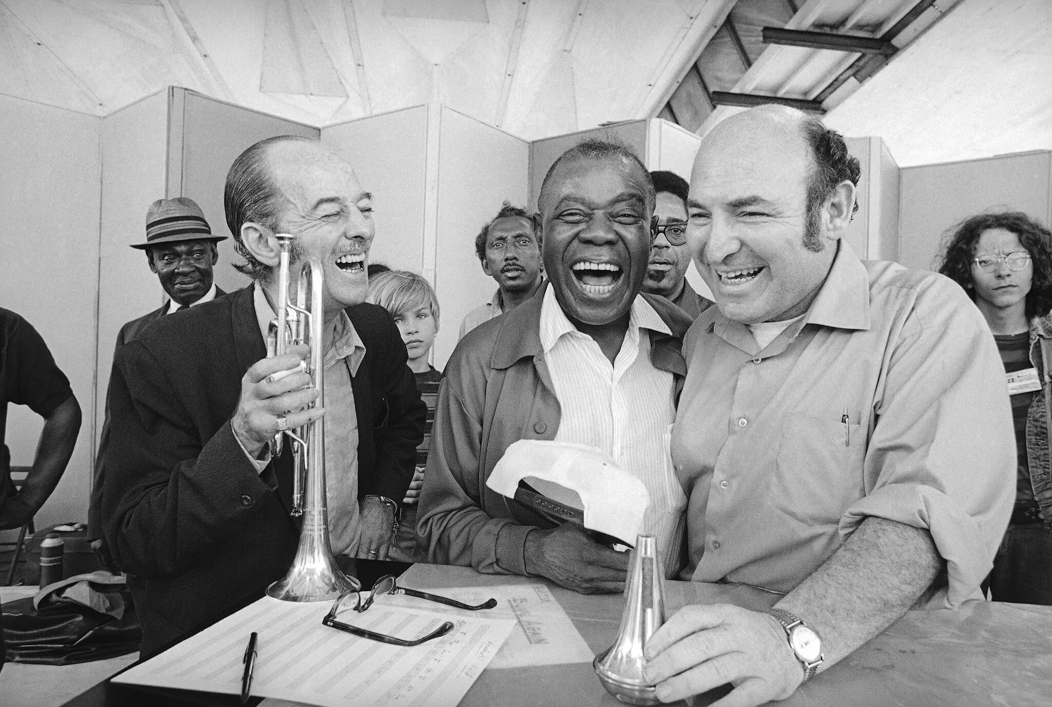 George Wein, à direita, com o trompetista Bobby Hackett e Louis Armstrong no Newport Jazz Festival em 1970. O festival, que o Sr. Wein apresentou pela primeira vez em 1954, se tornou um modelo de como apresentar música ao ar livre em grande escala.Crédito...J Walter Green/Associated Press