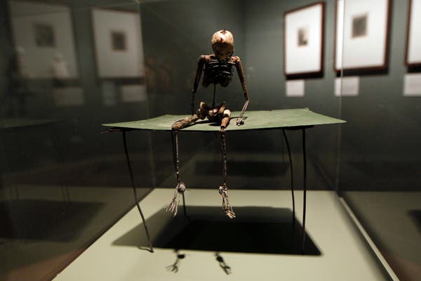 O talento da Sra. Leaf para o macabro ressurgiu em uma série de esqueletos no final de sua carreira — alguns pintados em tela ou metal e outros, como “Gentleman on Green Table” (2000), feitos de arame fino.Crédito...Sang Tan/Associated Press