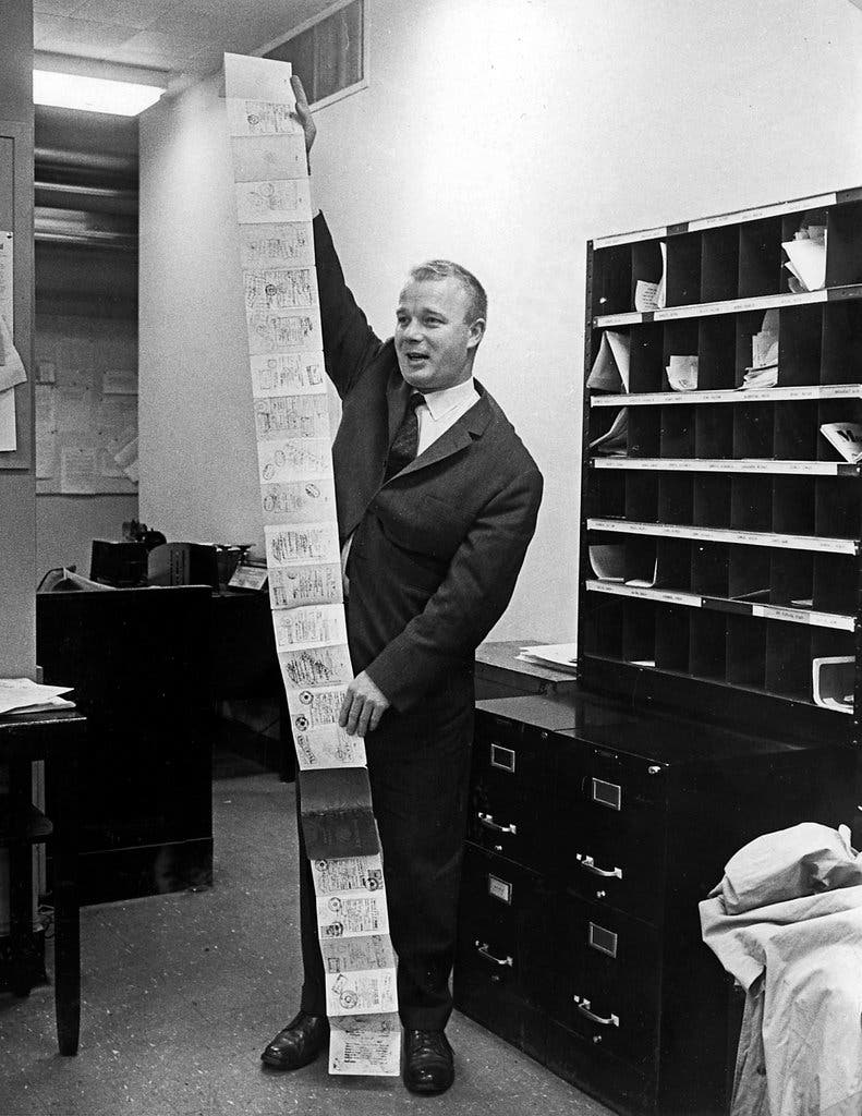 O correspondente do New York Times, David Binder, em 1966, com seu passaporte, um acordeão de 2,4 metros de páginas carimbadas com vistos de terras problemáticas.Crédito...O jornal New York Times
