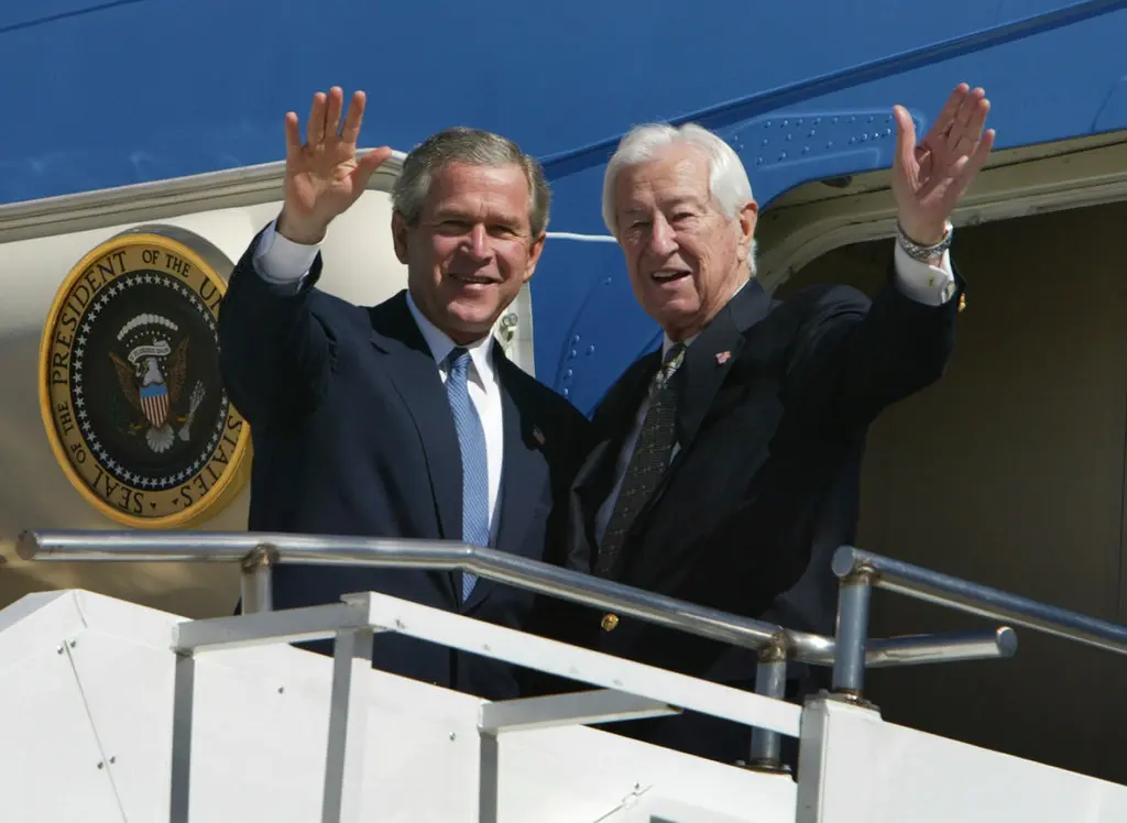 O Sr. Ralph Hall deixando o Força Aérea Americana em Dallas com o presidente George W. Bush em 2004. Depois de servir 12 mandatos no Congresso como democrata, o Sr. Hall mudou de partido naquele ano com o apoio do Sr. Bush. Crédito...Charles Dharapak/Associated Press