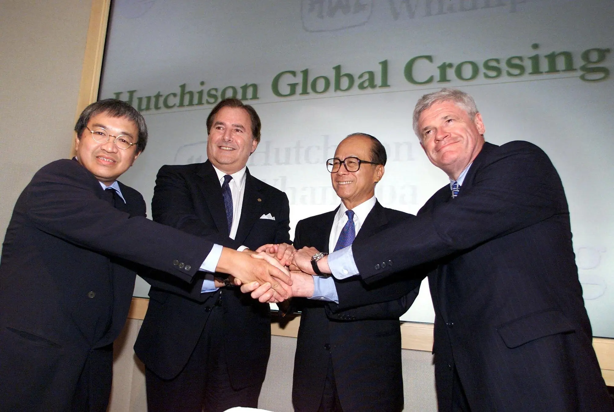 O Sr. Gary Winnick, o segundo da esquerda para a direita, em 1999, quando a Global Crossing e uma empresa de Hong Kong, a Hutchison Whampoa, formaram uma joint venture de telecomunicações e internet. Com ele, da esquerda para a direita, estavam Canning Fok, diretor-geral do grupo Hutchison; Li Ka-shing, seu presidente; e Jack Scanlon, diretor executivo da Asia Global Crossing. Posteriormente, a Hutchison e outra empresa asiática fizeram um investimento majoritário na Global Crossing.Crédito...Robyn Beck/Agence France-Presse — Getty Images