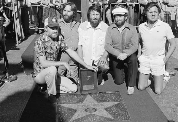 Os Beach Boys receberam uma estrela na Calçada da Fama de Hollywood em 1980. O Sr. Wilson está no centro; Bruce Johnston, que não era um membro original da banda, está na extrema direita.Crédito...Lennox McLendon/Associated Press