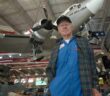 Conrad Shinn em 2016 no Museu Nacional de Aviação Naval em Pensacola, Flórida. Atrás dele está o avião que ele pousou no Polo Sul em 1956.Crédito...Tony Giberson/Pensacola News Journal