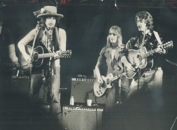 Da esquerda para a direita, Bob Dylan, Mick Ronson e o Sr. Neuwirth se apresentando em Toronto em 1975 como parte da turnê Rolling Thunder Revue do Sr. Dylan, na qual o Sr. Neuwirth foi fundamental na formação da banda.Crédito...Frank Lennon/Toronto Star via Getty Images