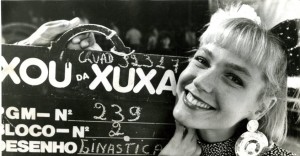 Xuxa Meneghel posa ao lado de uma claquete comemorando 239 edições do "Xou da Xuxa" 