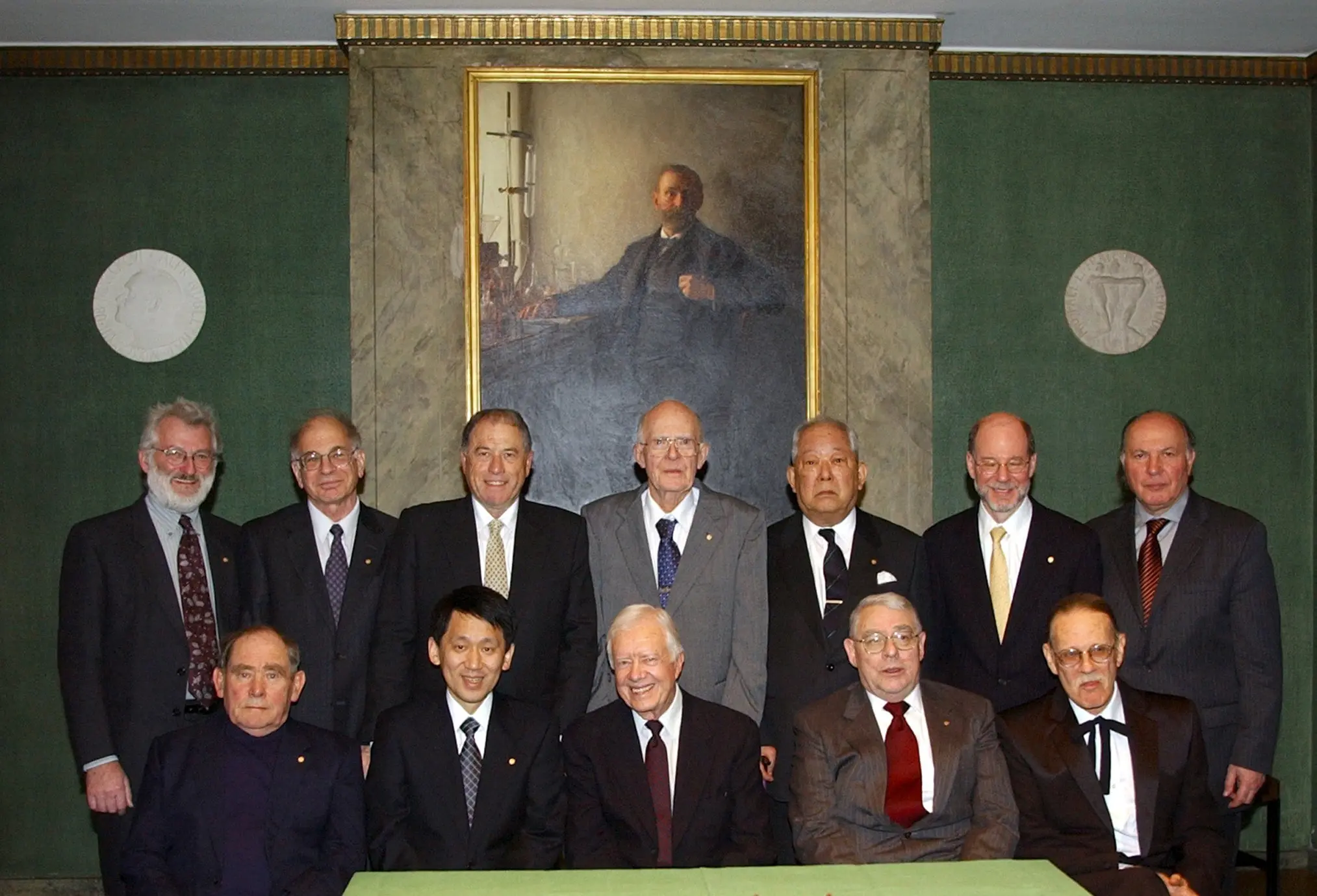 O professor Daniel Kahneman (em pé, segundo a partir da esquerda) reuniu-se com outros laureados com o Nobel de 2002 em Estocolmo, em Dezembro de 2002. Entre eles estava o ex-presidente Jimmy Carter (sentado, ao centro), que recebeu o Prémio da Paz. (Crédito da fotografia: Cortesia Fundação Nobel/Pressens Bild, via Associated Press)